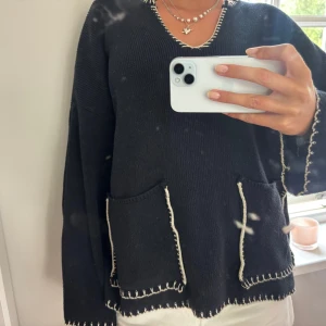 Svart stickad tröja med kontrastsömmar - Stickad tröja från Zara med fickor framtill och dekorativa sömmar i vitt. Strl S, bra skick 