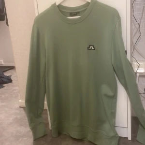 J.Lindeberg Crew Neck Sweat. - Grön J.Lindeberg tröja i storlek S som jag har växt ur. Tröjan har inga fläckar och är i fint skick förutom ett litet igensatt hål på ena sidan. (Bild finns!)