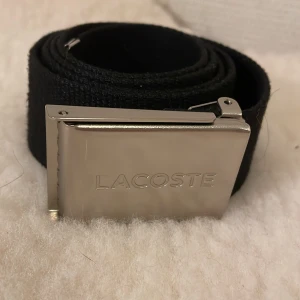 Lacoste bälte - Hej säljer mit gammla bälte den är i fint skick bara att det är lite av skärpet som har får upp från metall biten i slutet av skärpet men annars bra den är 90cm lång  pris kan diskuteras 