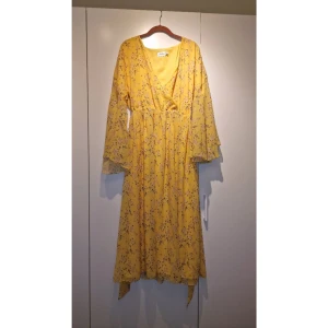 Gul Blommig Klänning - En fin och flowig klänning. Den är luftig så man svettas inte i den. Perfekt till midsommaren eller till en Brunch i utlandet. Endast använd 1 gång under midsommaren (sista bilden), så den är i superbra skick. 