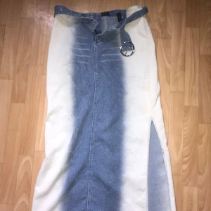 Jeanskjol från Sisters Point - Jeanskjol från Sisters Point i storlek S. Kjolen har en unik design med en bred blå jeansremsa i mitten och vita sidor. Den har en slits på sidan för extra stil och rörelsefrihet. Dessutom kommer den med ett matchande jeansbälte och glitter à la y2k