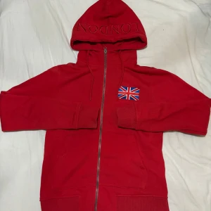 Luv tröja  - En röd luv tröja med en flagga på, och står london på luvan, aldrig använd