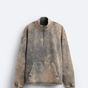 Brun och grå hoodie med dragkedja - Säljer en unik brun och grå hoodie med dragkedja och stor ficka framtill. Tröjan har en avslappnad passform och är perfekt för en cool och bekväm stil. Den har långa ärmar och en hög krage med dragkedja. Storlek M