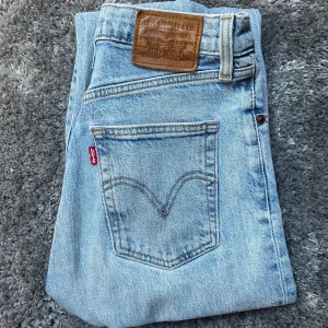 Ljusblå Levi's Jeans - Säljer ett par ljusblå Levi's jeans. De har en knappgylf, är högmidjade, rak passform, och kortare i byxlängden (är precis ner till marken på mig som är 162 cm lång)!