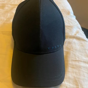 Mörkblå keps från Volvo - Snygg keps från Volvo med diskret broderad logotyp framtill. Perfekt för en stilren look. Kepsen har en klassisk design med böjd skärm och justerbar passform.
