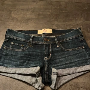 Mörkblå jeansshorts från Hollister - Snygga mörkblå jeansshorts från Hollister med låg midja och uppvikta ben. Dom är i storlek w26 och midjemåttet framtill är 41cm💗De är i bra skick och har används fåtal gånger.