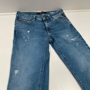 Blå jeans från Replay - Snygga blå jeans från Replay med en sliten look. De har en klassisk femficksdesign och en dragkedja. Perfekta för en avslappnad stil. Sitter ganska tajt.