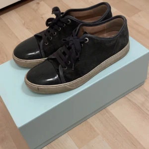 Svarta sneakers från Lanvin - Snygga svarta sneakers från Lanvin med snörning och en stilren design. Skorna har en kombination av skinn och mocka med en vit sula som ger en modern look. Perfekta för en trendig stil. (Det är storlek 40 passar också med 41 och riktigt sköna 