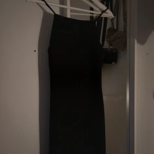 Svart klänning från MNG - Snygg svart klänning från MNG med smala axelband. Perfekt för en stilren look. Klänningen har en figurnära passform som framhäver silhuetten.