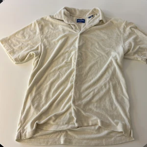 Beige kortärmad skjorta från Gant - Säljer en stilren beige kortärmad skjorta från Jack& Jones. Skjortan har en klassisk krage och knappar framtill. Perfekt för en avslappnad look.