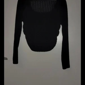 Svart långärmad tröja - Snygg svart långärmad tröja med ribbad struktur. Perfekt för en stilren look och kan matchas med olika outfits. Tröjan har en klassisk design som passar till många tillfällen.