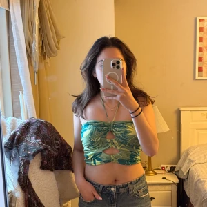 Grön blommig tubtopp - Säljer en grön blommig tubtopp från Zara. Toppen har ett tropiskt mönster i olika gröna nyanser och är perfekt för sommaren. Storlek M