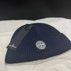 Stone Island Logo-Patch Beanie - Snygg mörkblå mössa från Stone Island med ribbad design och det ikoniska märket framtill. Perfekt för att hålla värmen med stil.