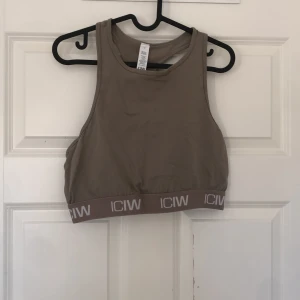 Beige träningstopp från ICANIWILL - Säljer en beige träningstopp från ICANIWILL i återvunnen nylon och spandex. Toppen har en elastisk kant med logotyp och är ärmlös med en sportig design. Perfekt för träning eller en aktiv vardag. Toppen är sååå snygg och man kan ha den under en annan tröja eller bara som den är, sjukt snyggt!!😍😍