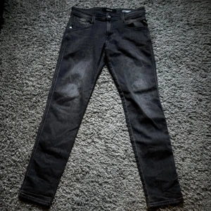 Mörkgrå Replay Jeans - Snygga svarta Replay Anbass jeans storlek 29/29 men passar även 30. Byxorna är i nyskick och använd fåtal gånger. Hårt och bra material, priset är inte hugget i sten. Skriv vid intresse!