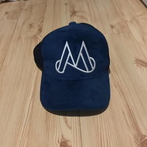 Blå keps från Maggiore - Snygg blå keps med vit broderad logga framtill. Kepsen har ett nätmaterial baktill för bättre ventilation och justerbar passform. Perfekt för en avslappnad stil. Ny pris är 549                              Kom gärna med prisförslag!