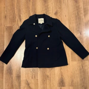 Marinblå skepparkavaj från Holly & Whyte - Snygg marinblå skepparkavaj från Holly & Whyte med stilrena guldknappar. Storlek 158, 12-13år. Skriv för fler bilder eller mått!