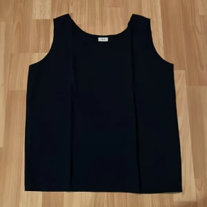 Marinblå ärmlös topp - Säljer en stilren marinblå ärmlös topp i storlek 38/40. Den är gjord av 55% viskos och 45% polyester, vilket gör den både bekväm och lätt att bära. Perfekt för både vardag och festliga tillfällen. Toppen har en enkel och elegant design som passar till det mesta. 🖤