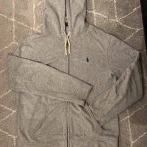 Ralph Lauren ziphoodie - Säljer nu denna riktigt snygga Ralph Lauren ziphoodien i färgen grå! Den är i väldigt bra skick och skönt material😇 vid ytterligare funderingar eller foton hör av dig 🤙🏼 Mvh John🍾
