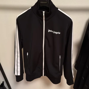 Palm Angels Tracksuit Tröja - Säljer en svart Palm Angels tracksuit jacka i storlek L. Finns en liten fläck på vänstra armen som inte går bort (se sista bilden) men annars i fint skick. Pris kan självklart diskuteras!