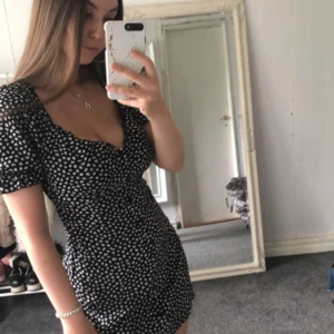 Svart kortklänning med vita prickar - Säljer en superfin svart kortklänning med vita prickar. Den har korta puffärmar och en söt v-ringning. Perfekt för sommarens alla fester! Klänningen är i nyskick och passar perfekt för en avslappnad men ändå stilren look.