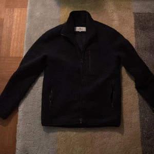 Mörkblå fleecejacka från John Henric - Säljer en stilren mörkblå fleecejacka från John Henric. Jackan har en dragkedja framtill och praktiska fickor med dragkedjor. Perfekt för kyliga dagar. 10/10 skick använt sparsamt!