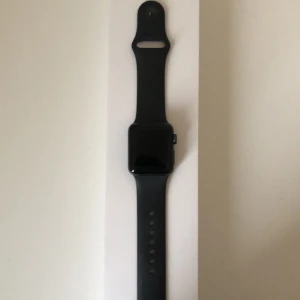 Svart Appel Watch Series 3 - Säljer en stilren svart Appel Watch Series 3. Klockan har en fyrkantig skärm och ett justerbart armband i svart. Kommer med originalförpackning. Nypris:1999kr