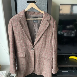 Kavaj Mango - Väldigt fin kavaj i feminin stil från Mango. Typ aldrig använd så behöver ett nytt hem.      Bystens längd: 48 cm Kavajens längd: 79 cm