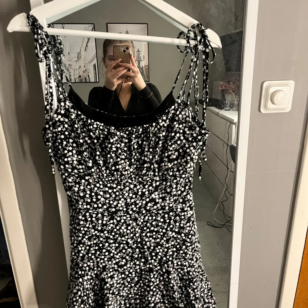 Fin blommig klänning med dragkedja och inbyggda shorts. Knytning på band. . Mekot.