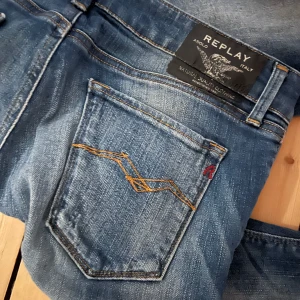 Blå jeans från Replay - Snygga blå jeans från Replay med coola slitningar och nitar vid fickorna. De har en klassisk femficksdesign och en knappgylf. Perfekta för en avslappnad stil. Och low waist pris går att diskutera. 
