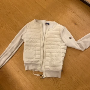 Vit moncler cardigan - Säljer en stilren vit jacka från Moncler med quiltade detaljer och dragkedja framtill. Älskar den!❤️