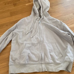 Beige hoodie från H&M - Säljer en beige hoodie från H&M Basic. Den har dragkedja framtill och en praktisk huva med dragsko. Fickor på magen och ribbade muddar vid ärmslut och nederkant. Perfekt för en avslappnad stil.