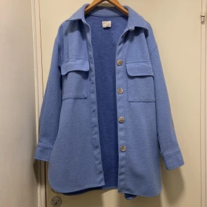 Blå overshirt med knappar - Snygg blå overshirt med stora knappar och två bröstfickor. Perfekt för lager-på-lager-stil. Den har en avslappnad passform och långa ärmar. PRIS KAN DISKUTERAS!