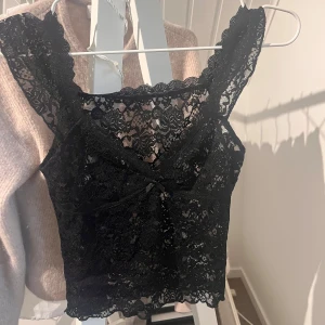 Svart spetslinne - Fint svart spetslinne med v-ringning och breda axelband. Aldrig använd 