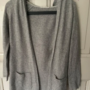 Grå kofta med fickor - Mysig grå kofta med långa ärmar och praktiska fickor framtill. Perfekt för kyliga dagar och enkel att matcha med olika outfits. Den har en avslappnad passform och är tillverkad i ett mjukt material.