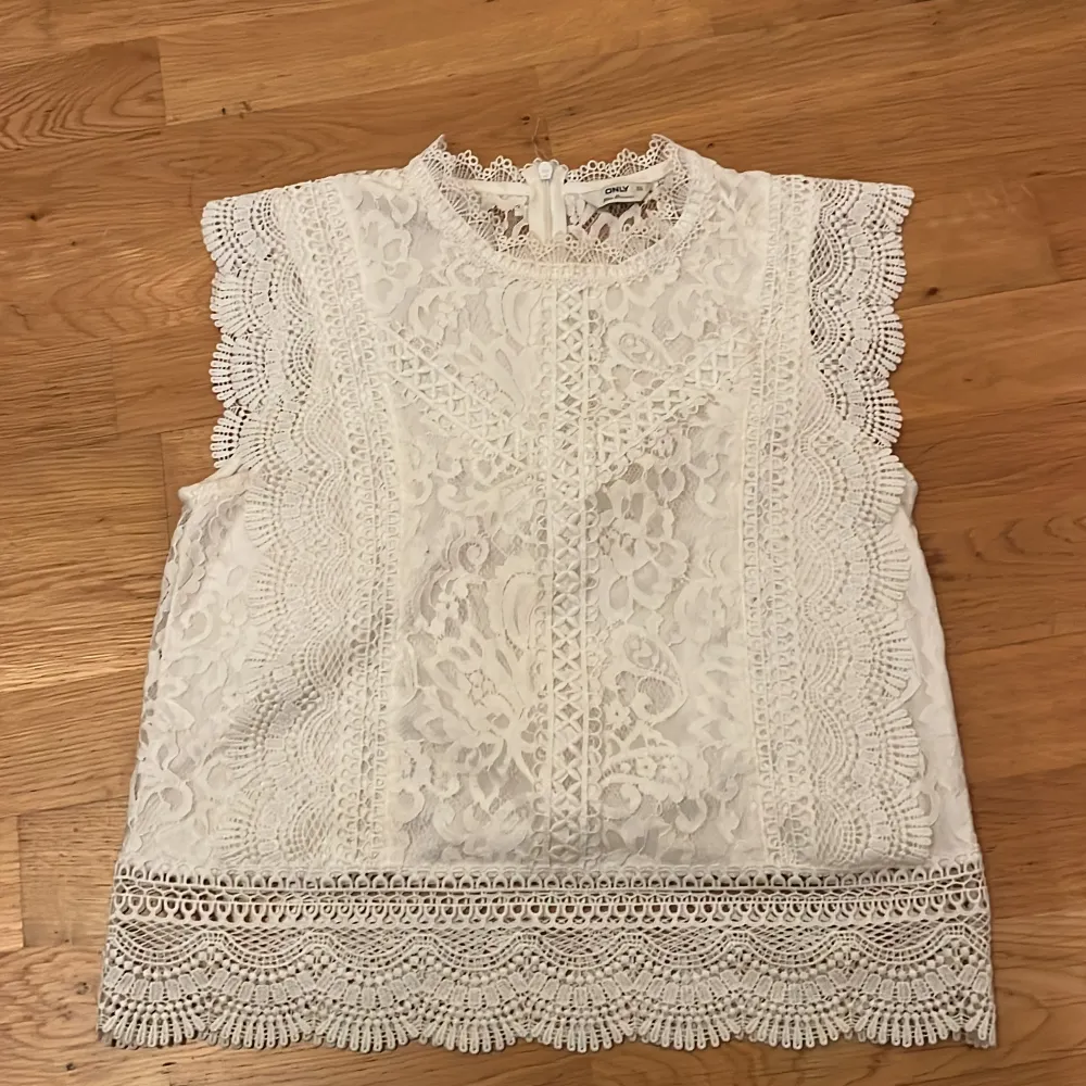 Säljer en söt vit spetsblus från Only i storlek XS. Blusen är ärmlös med vackra spetsdetaljer och en rund halsringning. Perfekt för en somrig look eller en speciell tillställning. Dragkedja i ryggen för enkel påklädning. Helt fel fri och använd 3 gånger pris kan alltid diskuteras ❤️. Yläosat.