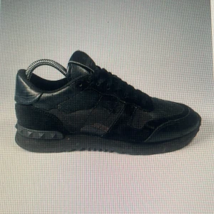 Svarta sneakers från Valentino - Snygga svarta sneakers från Valentino med en stilren design. Skorna har snörning och är tillverkade i en kombination av skinn och mocka. Perfekta för en trendig look. Kommer ta lite längre tid för att frakta den här produkten