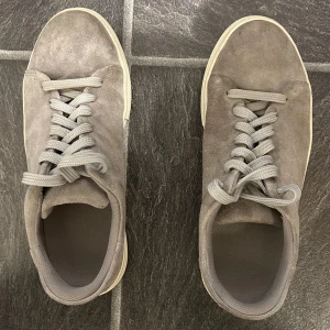 Grå sneakers från Selected Homme - Snygga grå sneakers i mocka från Selected Homme. Skorna har en klassisk design med snörning och en bekväm passform. Perfekta för en stilren look. Storlek 41