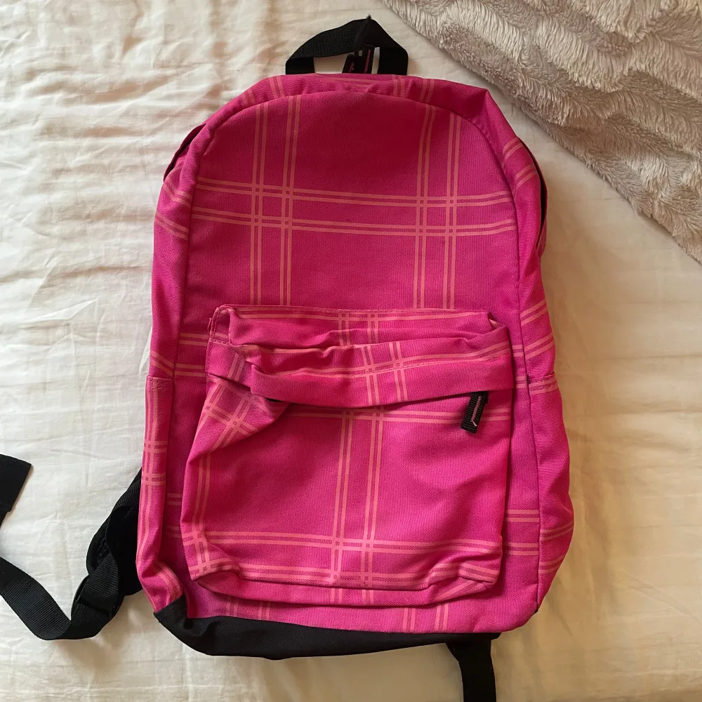 Säljer en snygg rosa ryggsäck med rutigt mönster. Väskan har en praktisk dragkedja och en framficka för extra förvaring. Perfekt för skolan eller utflykter! Många fickor i. 43cm hög, 28cm lång, 14cm djup. Laukut & Käsilaukut.