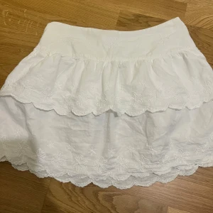 Vit kjol - Jättefin vit kjol med broderade blommor och volanger. 