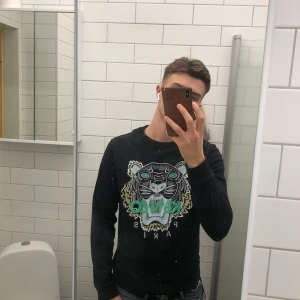 Kenzo sweatshirt  - Säljer en svart tröja från Kenzo med ett coolt tigertryck i grönt och vitt på framsidan. Tröjan har långa ärmar och en normal passform. Perfekt för dig som vill ha en stilren men ändå iögonfallande look.