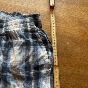 Rutiga pyjamasbyxor  - Säljer ett par bekväma rutiga byxor. De har en elastisk midja och ett klassiskt rutmönster i blått och vitt. Perfekta för en avslappnad stil.