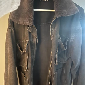 Svart jacka med fuskpäls från Boohoo - Säljer en snygg svart jacka från Boohoo i storlek M. Jackan har en mysig fuskpäls på kragen och ärmsluten, vilket gör den perfekt för kyligare dagar. Den har en dragkedja framtill och flera praktiska fickor. Jackan är i bra skick och redo för en ny ägare. Perfekt för höst och vinter!