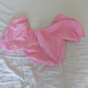 Rosa croppad topp från Gina Tricot - Säljer en superfin rosa croppad topp från Gina Tricot. Den har korta puffärmar och en söt knytning baktill. Perfekt för sommaren och festliga tillfällen! är i riktigt bra skick, använd 1 gång. Passar perfekt till ett par jeansshorts eller en kjol. 🌸🩷