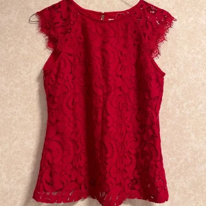 Röd spetsblus - Säljer en fin röd spetsblus. Den har ett vackert mönster i spetsmaterial. Perfekt för festliga tillfällen eller en utekväll.