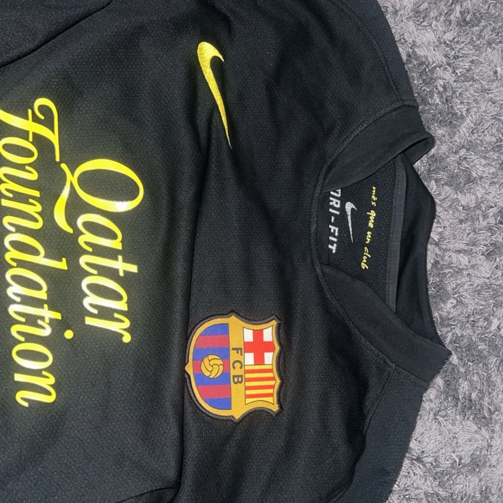 Säljer en svart långärmad FC Barcelona tröja från Nike. Tröjan har klubbens emblem på bröstet och Qatar Foundation som sponsor tryckt i gult på framsidan. Den är i Dri-Fit material och har LFP-märket på ärmen. Perfekt för alla Barca-fans! 💛Kunden står för frakten (pris kan diskuteras). T-shirts.