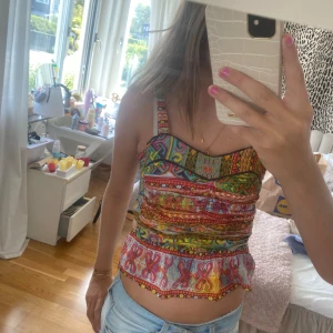 Färgglad mönstrad topp - Säljer en superfin färgglad topp med olika mönster. Toppen har smala axelband och en volangdetalj längst ner. Perfekt för sommaren och festliga tillfällen! 🌸