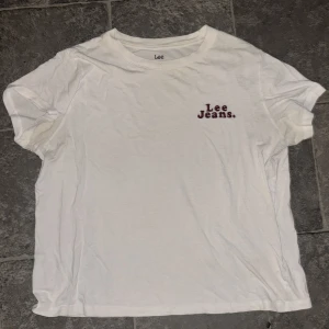 Vit t-shirt från Lee Jeans - Säljer en vit t-shirt från Lee Jeans i storlek S. T-shirten är gjord av bomull och har en normal passform. Den har korta ärmar och en enkel design med 'Lee Jeans' tryckt i rött på bröstet. Perfekt för en avslappnad vardagslook!