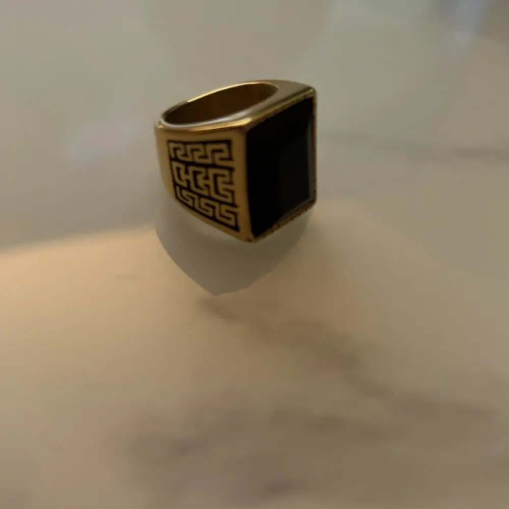 En guldfärgad ring med en svart Sten som får dig att sticka ut. Ringen är endast testad.. Accessoarer.