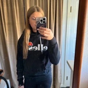 Svart hoodie från Ellesse - Säljer en svart hoodie från Ellesse i storlek 38. Den är superbekväm och perfekt för höst och vinter. Hoodien har en stor logga på framsidan och en praktisk ficka. Den är i fint skick och har långa ärmar.🖤